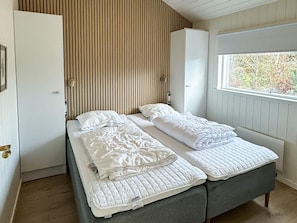 A bedroom with two beds, a window, and a wardrobe. - 5 Star Holiday Home in Vaeggerlose (Vaeggerlose)
