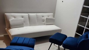 Un salon moderne avec un canapé blanc, deux fauteuils bleus et un plancher en bois.