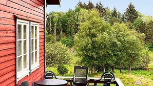 A red wooden building with a deck, two tables, and four chairs. - 6 Person Holiday Home in Finnas-by Traum (Bomlo)