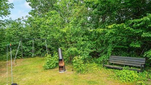 A grassy outdoor area with a swing set, a bench, and a cylindrical structure. - Tranquil Haven in Knebel (Knebel)