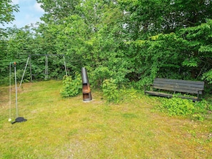 A grassy outdoor area with a swing set, a bench, and a cylindrical structure. - 6 Person Holiday Home in Knebel (Knebel)