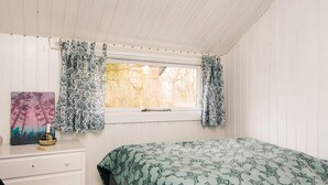 A bedroom with a bed, a desk, and a window with patterned curtains. - Tranquil Haven in Knebel (Knebel)