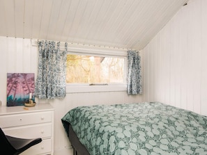 A bedroom with a bed, a desk, and a window with patterned curtains. - 6 Person Holiday Home in Knebel (Knebel)