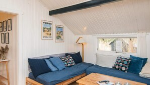 A cozy room with a wooden bench and a sofa, a small table with decorative items, and a window with a view of the outside. - Tranquil Haven in Knebel (Knebel)