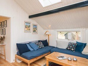 A cozy room with a wooden bench and a sofa, a small table with decorative items, and a window with a view of the outside. - 6 Person Holiday Home in Knebel (Knebel)