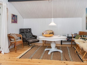 A cozy room with a white ceiling, a round table, a black leather chair, a wicker chair, and a white floor lamp. - 6 Person Holiday Home in Knebel (Knebel)