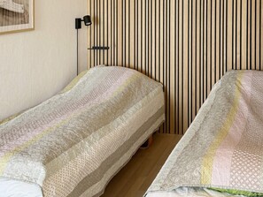 Una habitación con dos camas individuales, una lámpara fijada a la pared y un diseño de pared con listones de madera.
