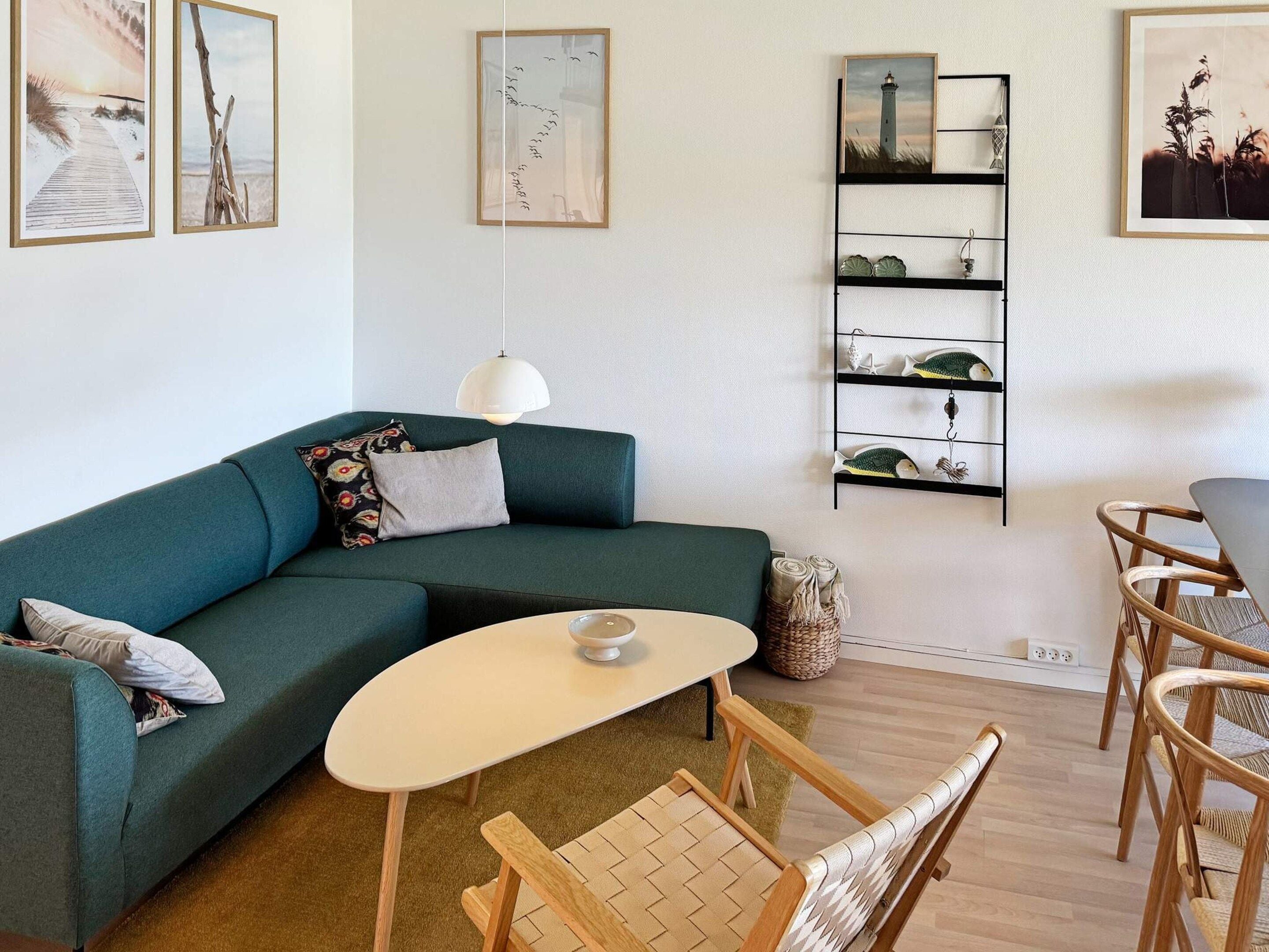 Un salon moderne avec un canapé de couleur turquoise, une petite table ronde et un fauteuil en osier.