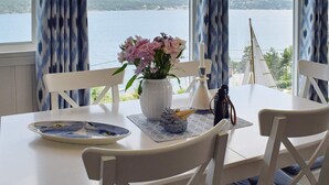 A dining table with a vase of flowers, a plate, a candle, and binoculars. - 8 Person Holiday Home in Filtvet (Asker)