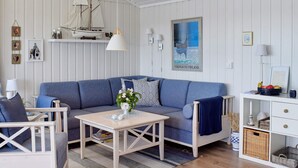 A cozy living room with a blue sofa, a wooden coffee table, and a white lamp. - 8 Person Holiday Home in Filtvet (Asker)