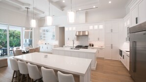 A modern kitchen with white cabinetry, a large island, and stainless steel appliances. - Luxury Modern Newly Built House in Naples (Naples)