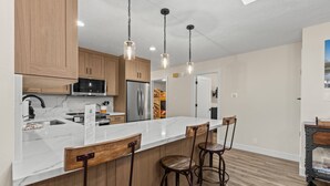 Eine moderne Küche mit Holzschränken, einer Marmorarbeitsplatte und einer Bar mit Hockern.