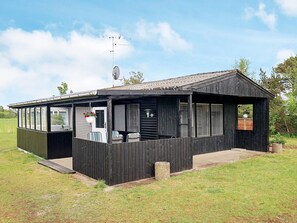 A wooden cabin with a covered porch, a satellite dish, and a small garden area. - 5 Person Holiday Home in Saeby (Sæby)