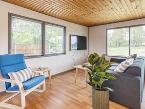 A modern living room with a blue chair, a grey sofa, a small table, and a large potted plant. - 5 Person Holiday Home in Saeby (Sæby)