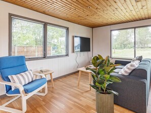 A living room with a blue chair, a grey sofa, a television, and a potted plant. - 5 Person Holiday Home in Saeby (Sæby)