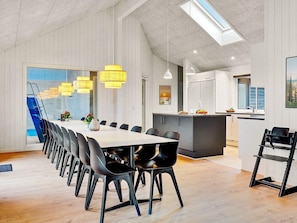 A modern dining area with a long table and chairs, a kitchen area with a refrigerator and sink, and a skylight above. - 5 Star Holiday Home in Sydals (Sydals)