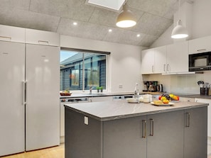 A modern kitchen with a large island, stainless steel appliances, and a view of a house through the window. - 5 Star Holiday Home in Sydals (Sydals)