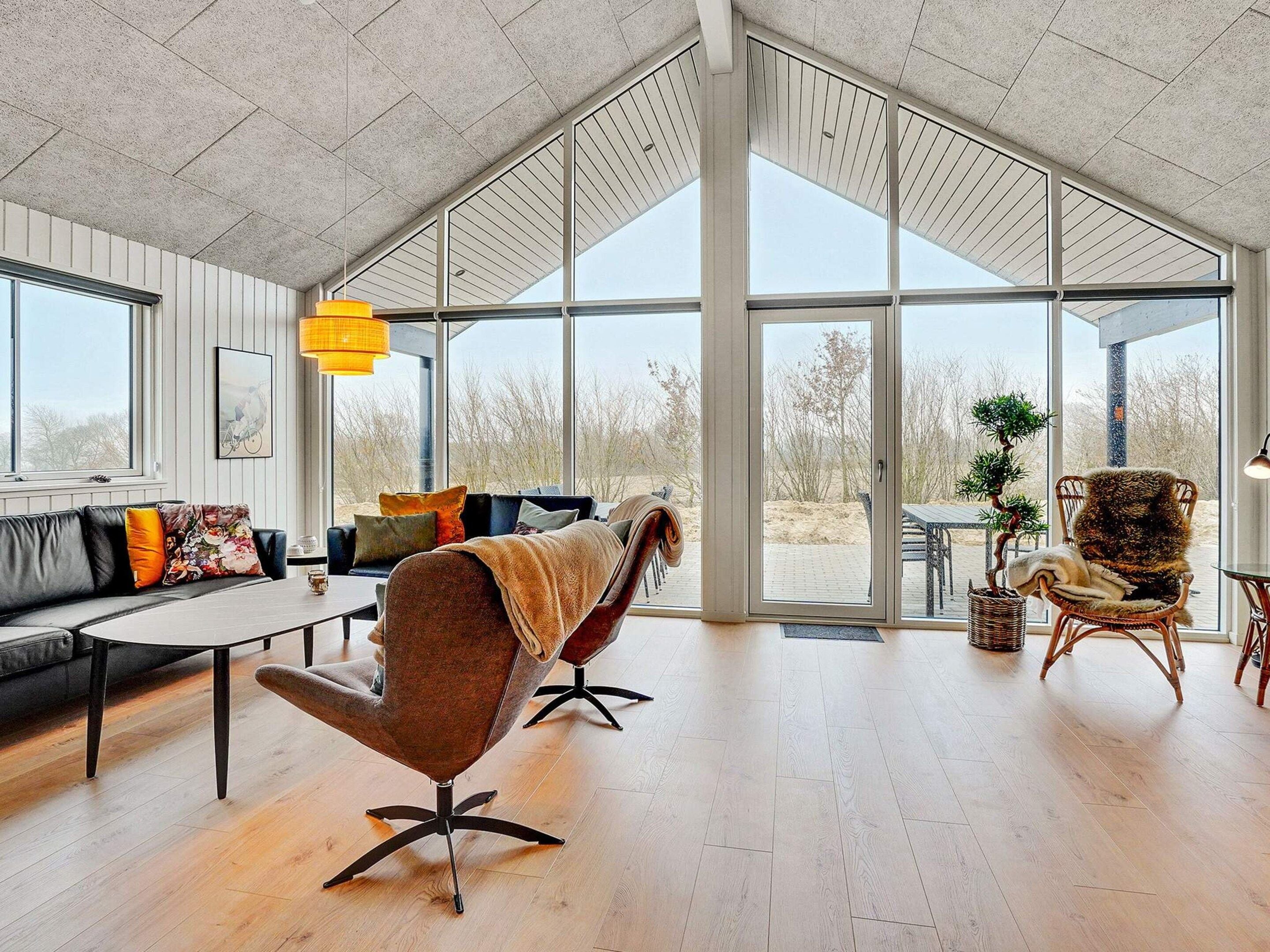 A spacious living area with a large window, a sofa, a coffee table, and a chair.
