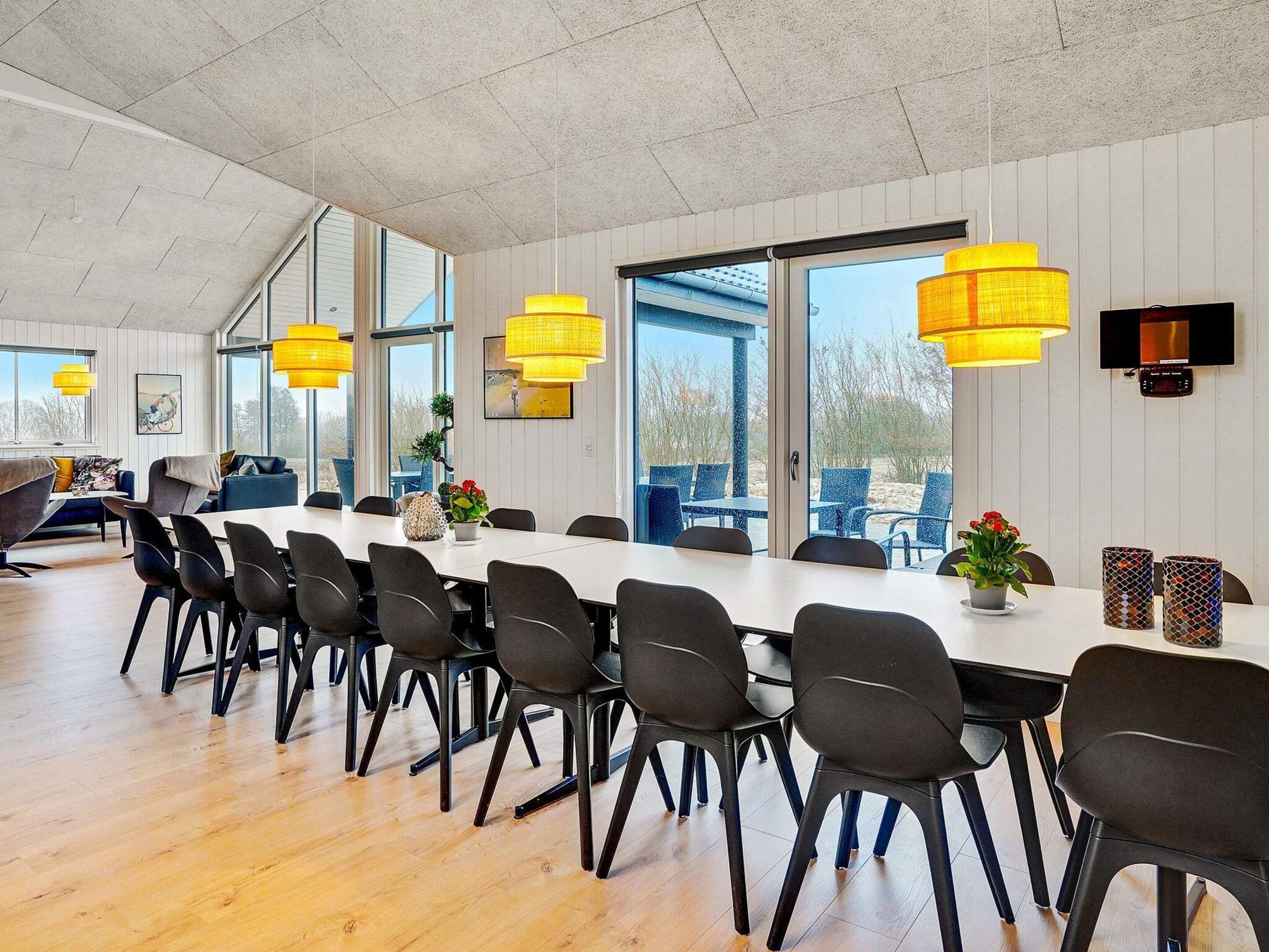A spacious dining area with a long table, multiple chairs, and pendant lighting.