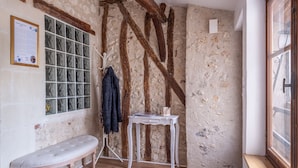 Ein rustikales Zimmer mit sichtbaren Holzbalken, einer Bank, einem kleinen Tisch mit Buch und Tasse sowie einem Fenster mit Aussicht.