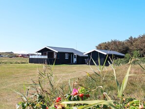A black building with a sloped roof, surrounded by a grassy field and trees.