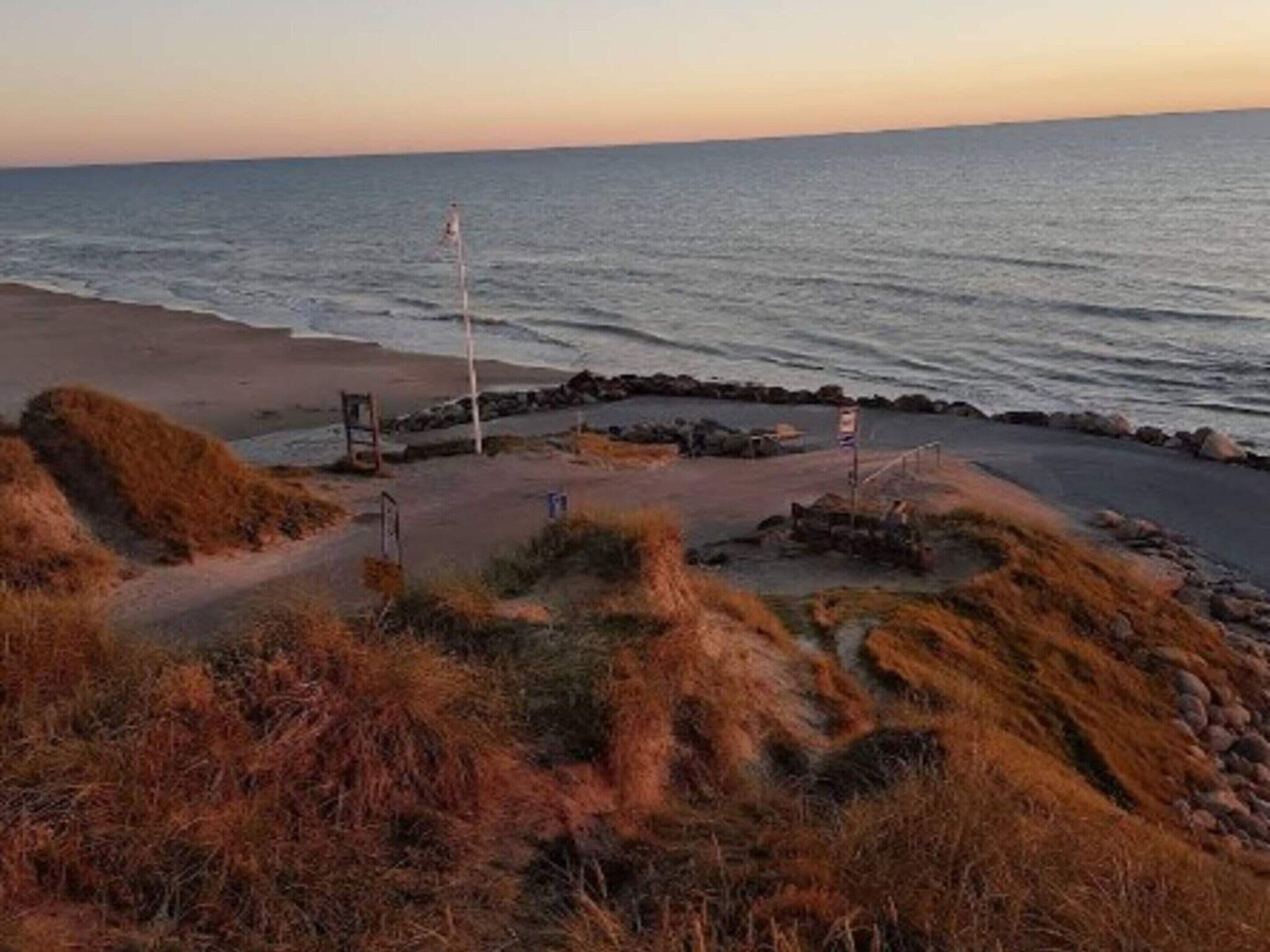 Egy partszakaszhoz tartozó, sziklás akadályokkal ellátott ösvény, egy útbaigazító tábla és egy a strandhoz vezető, burkolt gyalogút.