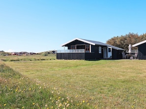 A modern house with a large open porch, a fenced yard, and a clear sky. - 4 Person Holiday Home in Lokken (Lokken)