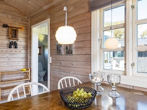 A wooden interior with a dining table, chairs, a basket of fruit, and a window with a view. - 4 Person Holiday Home in Lokken (Lokken)