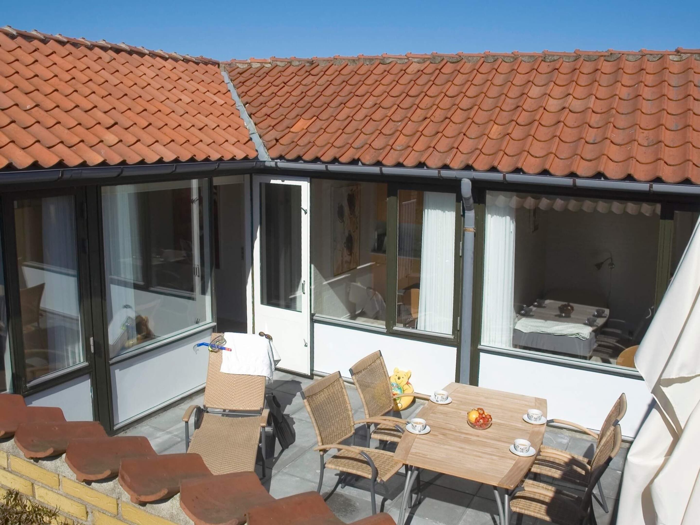 Un patio techado con una mesa de comedor, sillas y una pequeña zona de estar.
