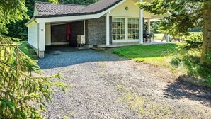 A two-story house with a garage, a covered porch, and a gravel driveway.
