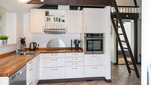 A modern kitchen with white cabinets, a stainless steel oven, and a wooden countertop.