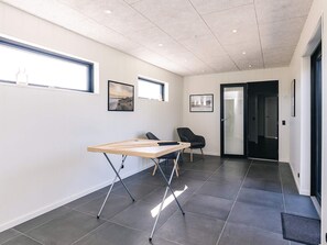 Un espace de bureau moderne, doté d’un bureau réglable en hauteur, de deux chaises, de tableaux encadrés accrochés au mur et d’une porte donnant sur une autre pièce.