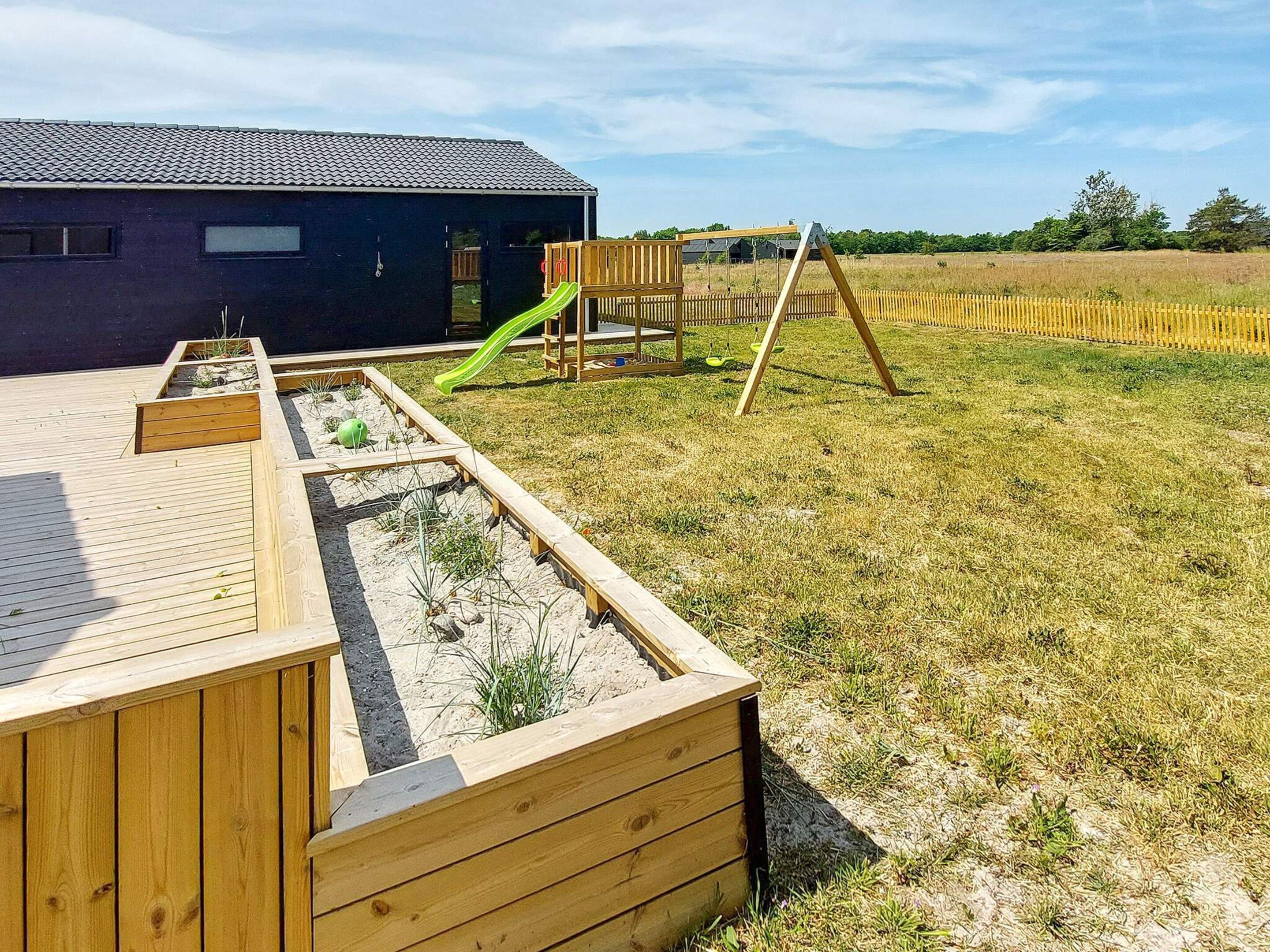 A wooden deck with a play area including a slide and a swing set.