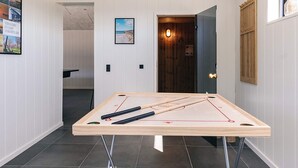 Una habitación con mesa de ping pong, una puerta de madera y un cuadro en la pared.