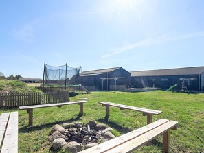 A grassy outdoor area with picnic tables, a fire pit, and a building with a roof. - 8 Person Holiday Home in Jerup-by Traum (Jerup)