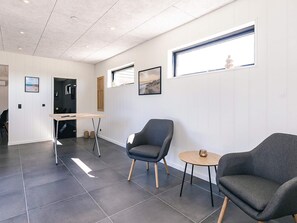 A modern interior with a dining area, two grey armchairs, a small round table, and a window with a view. - 8 Person Holiday Home in Jerup-by Traum (Jerup)