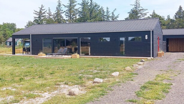 Una casa moderna con un porche cubierto, un garaje y el número 6 en el lateral.