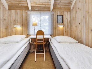 A room with two single beds, a wooden desk, a chair, a window with curtains, and wall-mounted lamps. - 8 Person Holiday Home in Fjerritslev (Fjerritslev)