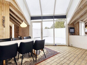 A dining area with a table and chairs, a patterned rug, and a television on a stand. - 8 Person Holiday Home in Fjerritslev (Fjerritslev)