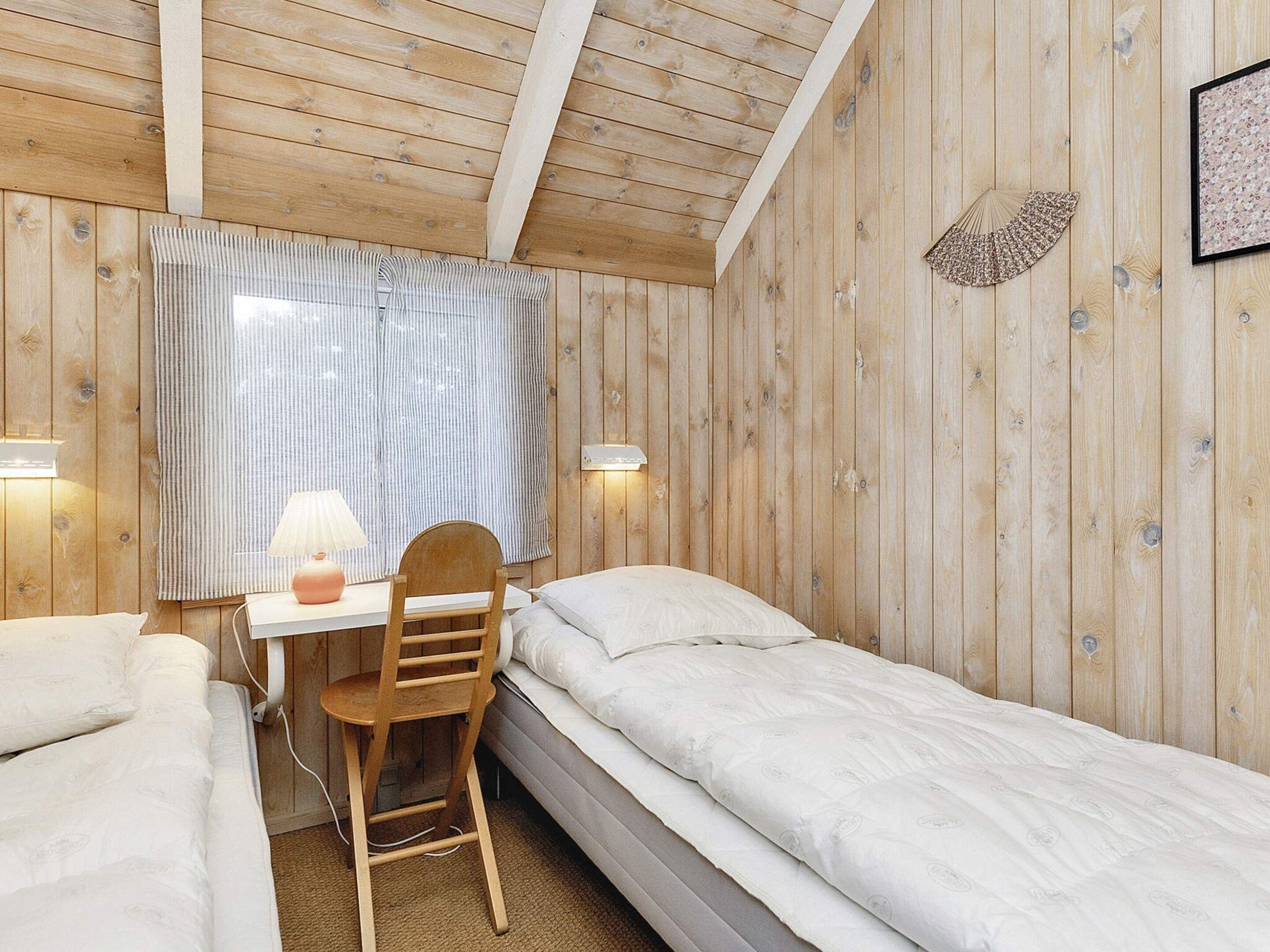Ett rum med träpanel på väggarna, ett rum som innehåller en säng, ett skrivbord och en stol.