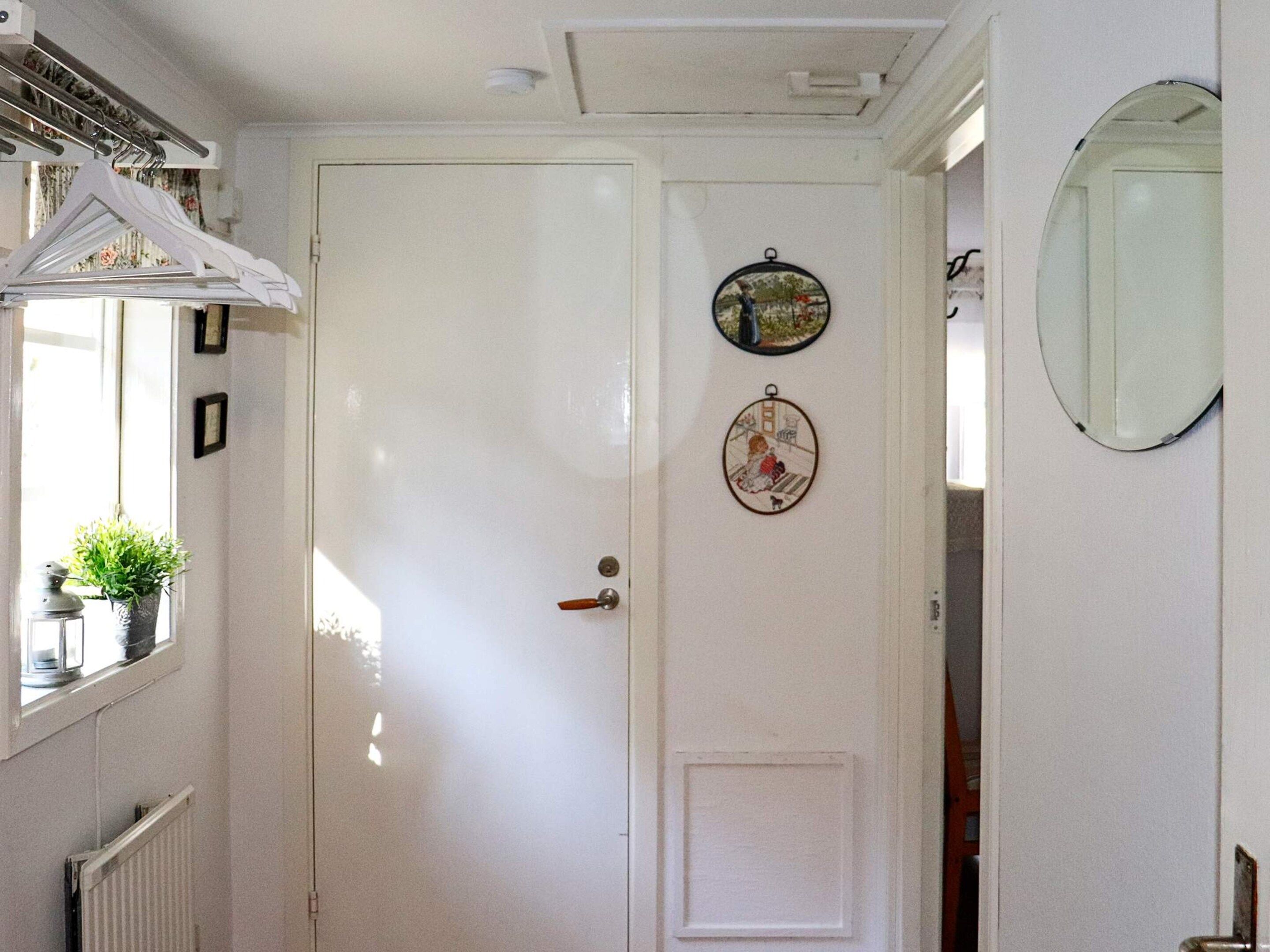 A white door with a round mirror and two framed pictures on the wall.