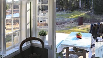 A wooden deck with a table and chairs, overlooking a forested area.