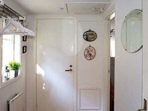 Una porta blanca amb un pom, una finestra petita amb una planta, i un mirall a la paret.