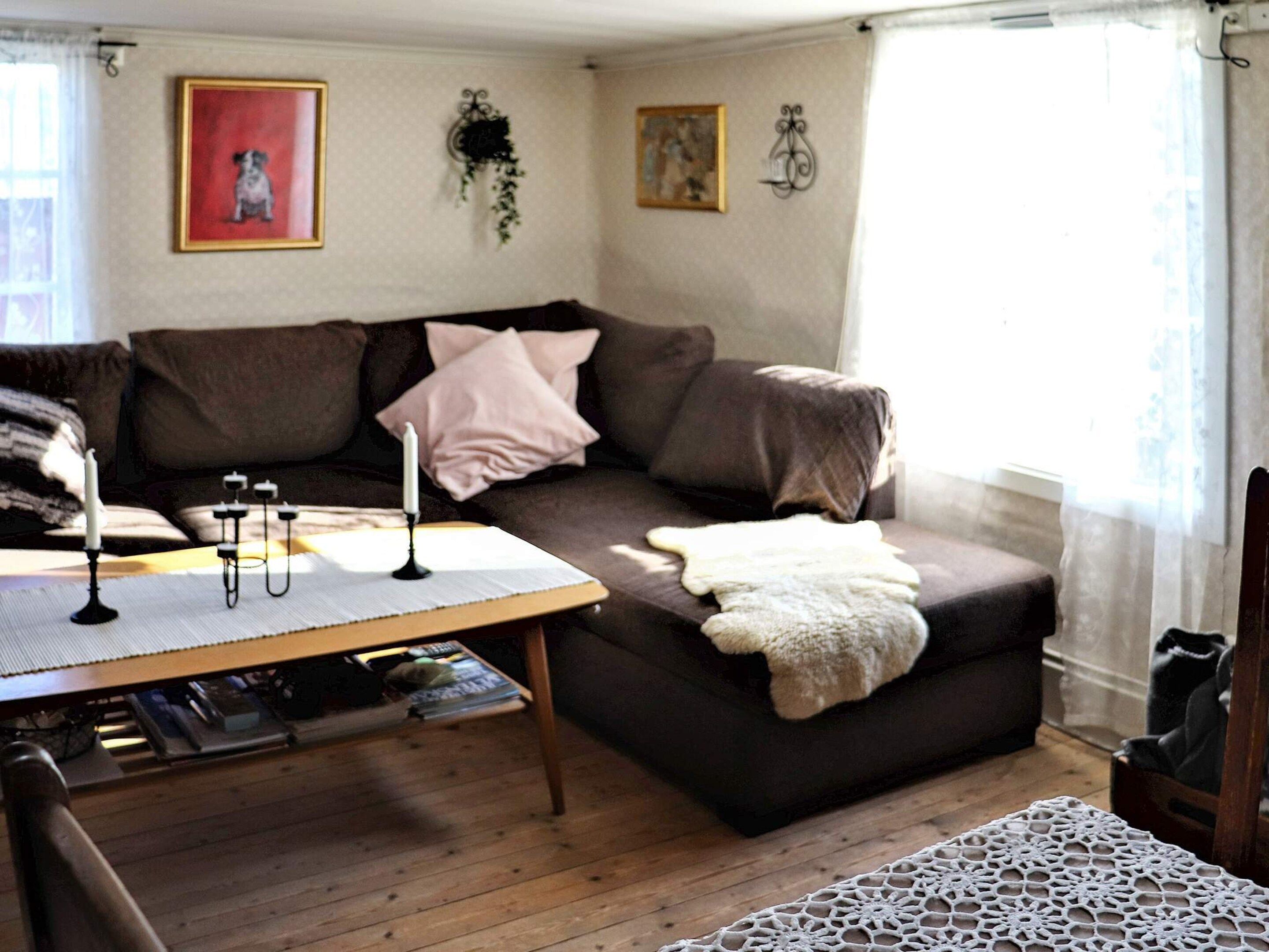 Una sala de estar acogedora con un sofá marrón, una mesa de centro de madera y una alfombra estampada.
