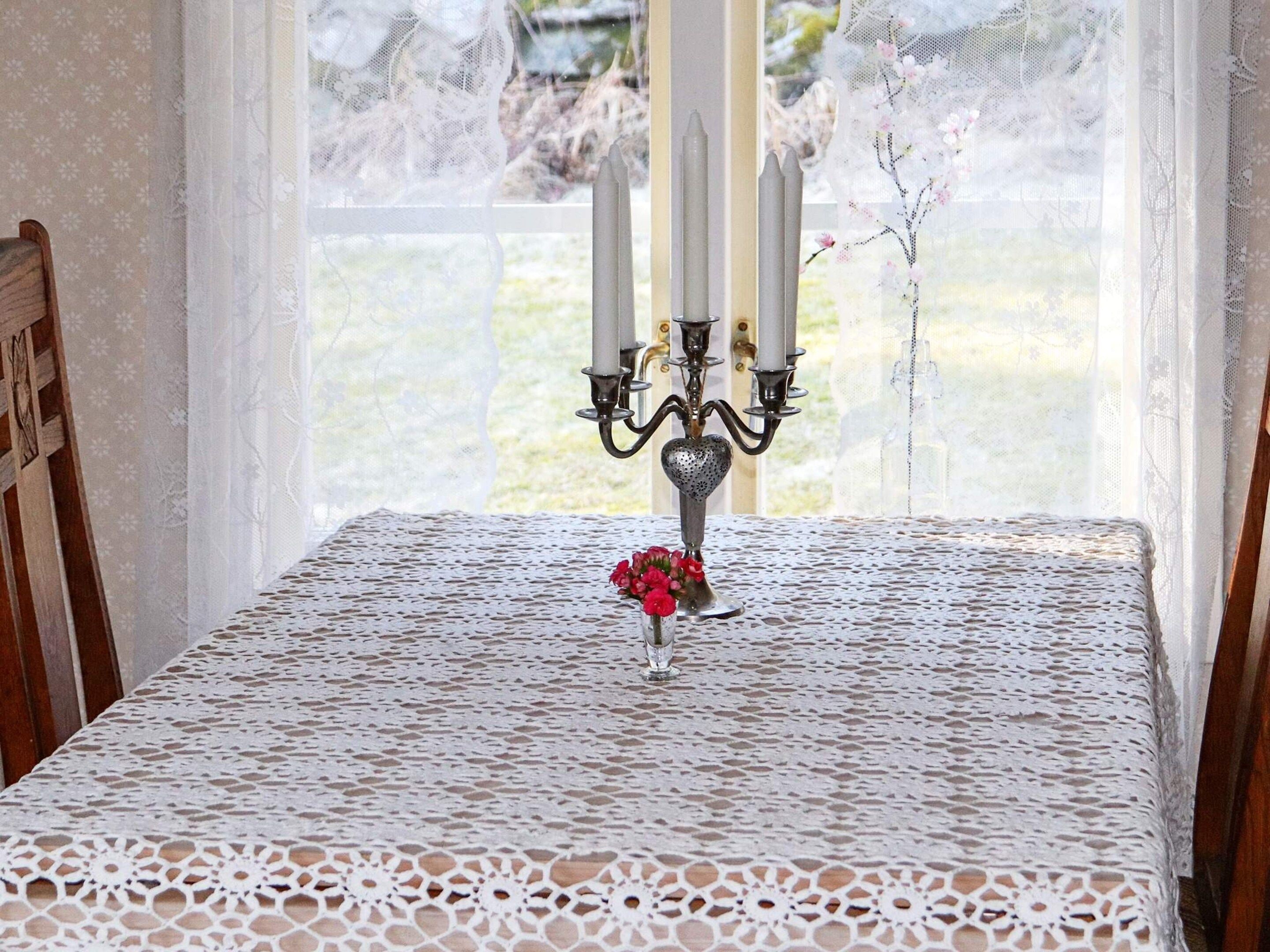A table with a lace tablecloth, a candelabra, and a vase with flowers.