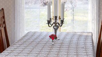 A table with a lace tablecloth, a candelabra, and a vase with flowers.