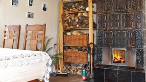 A cozy room with a fireplace, wooden shelves with logs, a lace tablecloth, and chairs. - 5 Person Holiday Home in Fjaras (Fjärås)