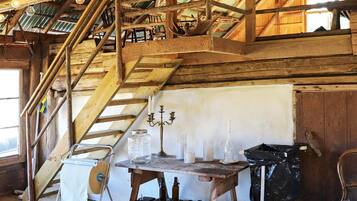 A rustic interior with a wooden staircase, a table with various items, and a chair.