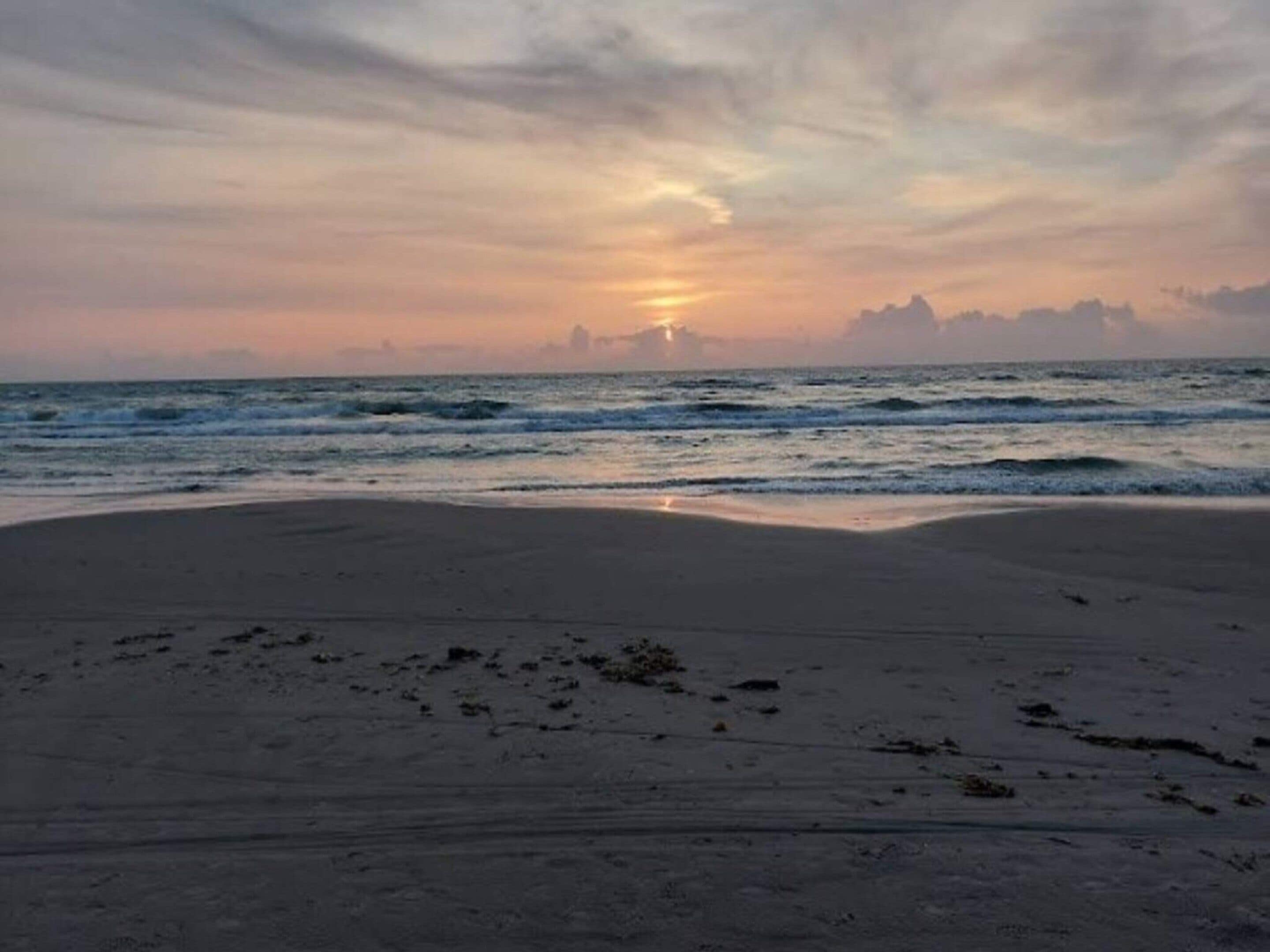 A beach with a sunset over the ocean.