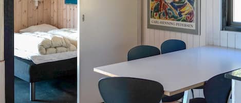 Una habitación con cama, una mesa y sillas. Hay un cuadro en la pared y una ventana.